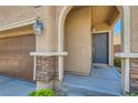 Close-up on the home's entryway with a gray front door, stylish sconces, and stacked stone details at 10744 Yarmouth Bay Ct, Las Vegas, NV 89179