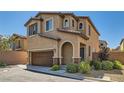 Two-story home featuring a two-car garage, neutral stucco, a low-maintenance yard, and an arched front door at 10744 Yarmouth Bay Ct, Las Vegas, NV 89179