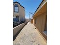 Side exterior view of a tan single story home with gravel landscaping at 2417 St George St, North Las Vegas, NV 89030