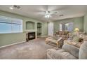 Comfortable living room featuring a fireplace and neutral-toned carpet with bright natural light at 9165 Starling Wing Pl, Las Vegas, NV 89143