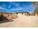 Single-story home with an extra long driveway, an attached garage, neutral colors, and desert landscaping at 9340 W Washburn Rd, Las Vegas, NV 89149