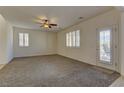 Bright living room featuring neutral walls, ceiling fan, carpeting, and a glass door leading to outdoor space at 952 Crescent Falls St, Henderson, NV 89011