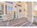 Cozy front porch featuring decorative plants, a small chair, and a charming wreath on the front door at 1035 Tabor Hill Ave, Henderson, NV 89074