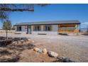 Single-story home with neutral siding, dark trim, wood-look shutters, and arid landscaping at 1050 Bruce St, Pahrump, NV 89048
