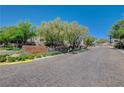 Community entrance sign at Summerlin Hills with lush landscaping and mature trees along brick paved road at 11280 Granite Ridge Dr # 1035, Las Vegas, NV 89135
