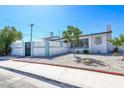 Charming home with white fence, decorative rock landscaping, and a lion design, adding unique curb appeal at 1521 Sombrero Dr, Las Vegas, NV 89169