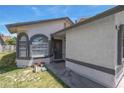 Close-up shot of a home's front entry featuring arched windows, a stucco facade, and green lawn at 1622 Lorna Dr, Henderson, NV 89011