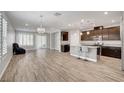 Bright, open-concept living space featuring a kitchen island, chandelier, and wood-style tile floors at 2238 Thelen Ave, North Las Vegas, NV 89086