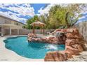 Inviting pool area with a rock waterfall feature, a gazebo, and built-in outdoor grill at 358 Whispering Tree Ave, Las Vegas, NV 89183