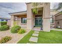 Home entrance with a beautiful green door, manicured landscaping, and walkway at 6060 N Conquistador St, Las Vegas, NV 89149