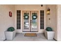 Elegant double front doors adorned with wreaths, flanked by decorative planters and sconce lighting at 7310 Heggie Ave, Las Vegas, NV 89131