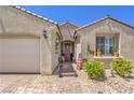 Inviting home entrance with brick walkway, decorative accents, and a well-manicured garden area and a two-car garage at 8269 Skye Peak St, Las Vegas, NV 89166