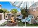 Inviting outdoor living space features a cozy fire pit, comfortable seating, and a stylish umbrella for shade at 8629 Prairie Hill Dr, Las Vegas, NV 89134