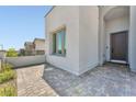 Close-up of a modern home's arched entry, featuring a neutral stucco exterior and a brick driveway at 11707 Hatchling Ave, Las Vegas, NV 89138