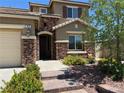 Charming two-story home with a stone facade, landscaped yard, and a welcoming entrance with an arched doorway at 368 Misty Moonlight St, Henderson, NV 89015