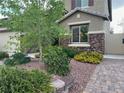 Landscaped front yard with mature trees, colorful flowers, and a brick pathway leading to the home's entrance at 368 Misty Moonlight St, Henderson, NV 89015