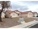 Exterior shot of single story home with desert landscaping, tile roof, and side view of a tree in the yard at 4618 Zia Ridge St, North Las Vegas, NV 89031
