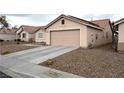 Tan single-story home with a two-car garage, low maintenance desert landscaping, and a long driveway at 4618 Zia Ridge St, North Las Vegas, NV 89031