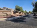 Gated community entrance with brick walls, mature trees, and well-maintained landscaping at 7380 Abundant Harvest Ave, Las Vegas, NV 89131
