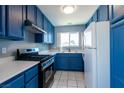 Well-lit kitchen equipped with blue cabinets, modern appliances, and a window offering natural light at 7728 Barbican Ct, Las Vegas, NV 89147