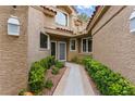 Inviting home entrance with a tiled walkway, green bushes, and stucco walls at 7988 Harbour Towne Ave, Las Vegas, NV 89113