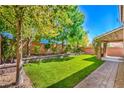 Lush backyard featuring a well-maintained lawn, mature trees, and a charming covered patio at 10116 Nash Peak Ave, Las Vegas, NV 89166