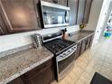 Stylish kitchen featuring stainless steel appliances, granite countertops, dark wood cabinetry, and tile flooring at 10383 Andele Ave, Las Vegas, NV 89166