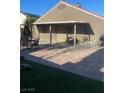 View of covered patio with brick pavers, patio furniture, and green grass at 3443 Citruscedar Way, North Las Vegas, NV 89032
