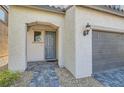 Stylish front entrance showcasing a paved walkway, stucco walls, and a cozy covered entryway with a gray-blue front door at 6938 Feather Hill St, North Las Vegas, NV 89086