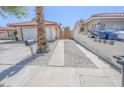 Long driveway leading to a detached garage, with desert landscaping and a wooden gate visible in the background at 134 Saint Albans Dr, Henderson, NV 89015