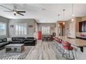 Open-concept living room featuring a large black leather sectional sofa, wood floors, and kitchen breakfast bar at 468 Harvest Rain, Las Vegas, NV 89011