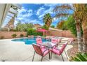 Relaxing pool area with rock features, lush palm trees, and comfortable patio furniture at 5024 Granite Creek Ct, Las Vegas, NV 89131