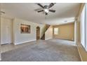 Bright living room features neutral carpeting, ceiling fan, staircase, and an archway leading to the kitchen at 6381 Pronghorn Ridge Ave, Las Vegas, NV 89122