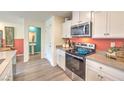 Well-lit kitchen featuring white cabinets, stainless steel appliances, and a view into the half bathroom at 6918 Wrightshire St # 24, Las Vegas, NV 89166