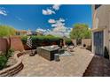 Outdoor brick patio with stylish seating, lush greenery, and privacy fencing at 7486 Benlomond Ave, Las Vegas, NV 89179