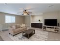 Comfortable living room with a large sectional sofa, ceiling fan, TV, and dark wood accents at 9469 Coral Shine Ct, Las Vegas, NV 89123