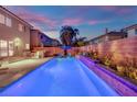 Inviting outdoor pool area with an outdoor kitchen, comfortable lounge chairs, and lush landscaping at 10902 Fintry Hills St, Las Vegas, NV 89141