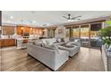Open living room featuring a large sectional sofa, hardwood floors, and sliding glass doors to the backyard at 12430 Foxtail Run Ave, Las Vegas, NV 89138