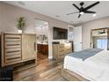 Calm main bedroom featuring wood-like floors, modern furniture, a ceiling fan, and an en-suite bathroom at 12430 Foxtail Run Ave, Las Vegas, NV 89138