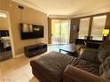 Relaxing living room with a large sectional sofa, TV, and sliding glass doors opening to a balcony at 210 E Flamingo Rd # 215, Las Vegas, NV 89169