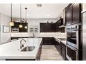 Modern kitchen featuring dark cabinets, a large island, stainless steel appliances and wood-look tile flooring at 352 Dandelion Brook Ct, Las Vegas, NV 89148