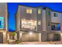 Exterior view of townhome at night with balcony, neutral paint, garage and desert landscaping at 6821 Prairie Pearl St, Las Vegas, NV 89148