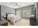 Bright bedroom with a ceiling fan, large windows, and a comfortable bed with floral bedding at 7641 Lani Dawn St, Las Vegas, NV 89149