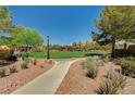 Lush green space with mature trees, park benches, and a walking path, creating a serene outdoor environment at 8129 Jim Steele Falls St, North Las Vegas, NV 89085