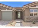 Inviting front entrance with a stone accent wall, desert landscaping, and a well-lit walkway at 8316 Broad Peak Dr, Las Vegas, NV 89131