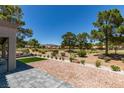 Backyard view with mature trees, desert landscaping, golf course view, and covered patio at 9520 Sundial Dr, Las Vegas, NV 89134