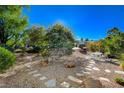 Beautiful backyard featuring desert landscaping and a stone patio with outdoor seating at 10302 Cara Mia Ct, Las Vegas, NV 89135