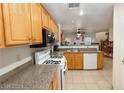 Functional kitchen featuring oak cabinets, granite countertops, and white appliances at 1259 Plum Canyon St, Las Vegas, NV 89142