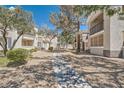 Exterior of condos featuring desert landscaping, shade trees, and a sidewalk offering a peaceful and walkable community at 2325 Windmill Pkwy # 312, Henderson, NV 89074