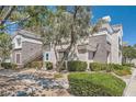 A sunlit exterior view of a condo featuring a private stairwell, trimmed bushes, and desert-friendly landscaping at 2325 Windmill Pkwy # 312, Henderson, NV 89074